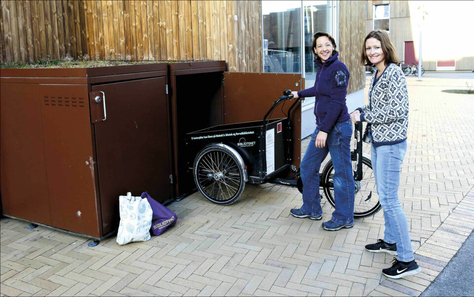 Sykkelgarasjene. Bibliotekar Tove Rudi Tanem låner ut elektrisk lastesykkel til Judith van Hagen. Her står de ved sykkelgarasjene som rommer to elektriske lastesykler.